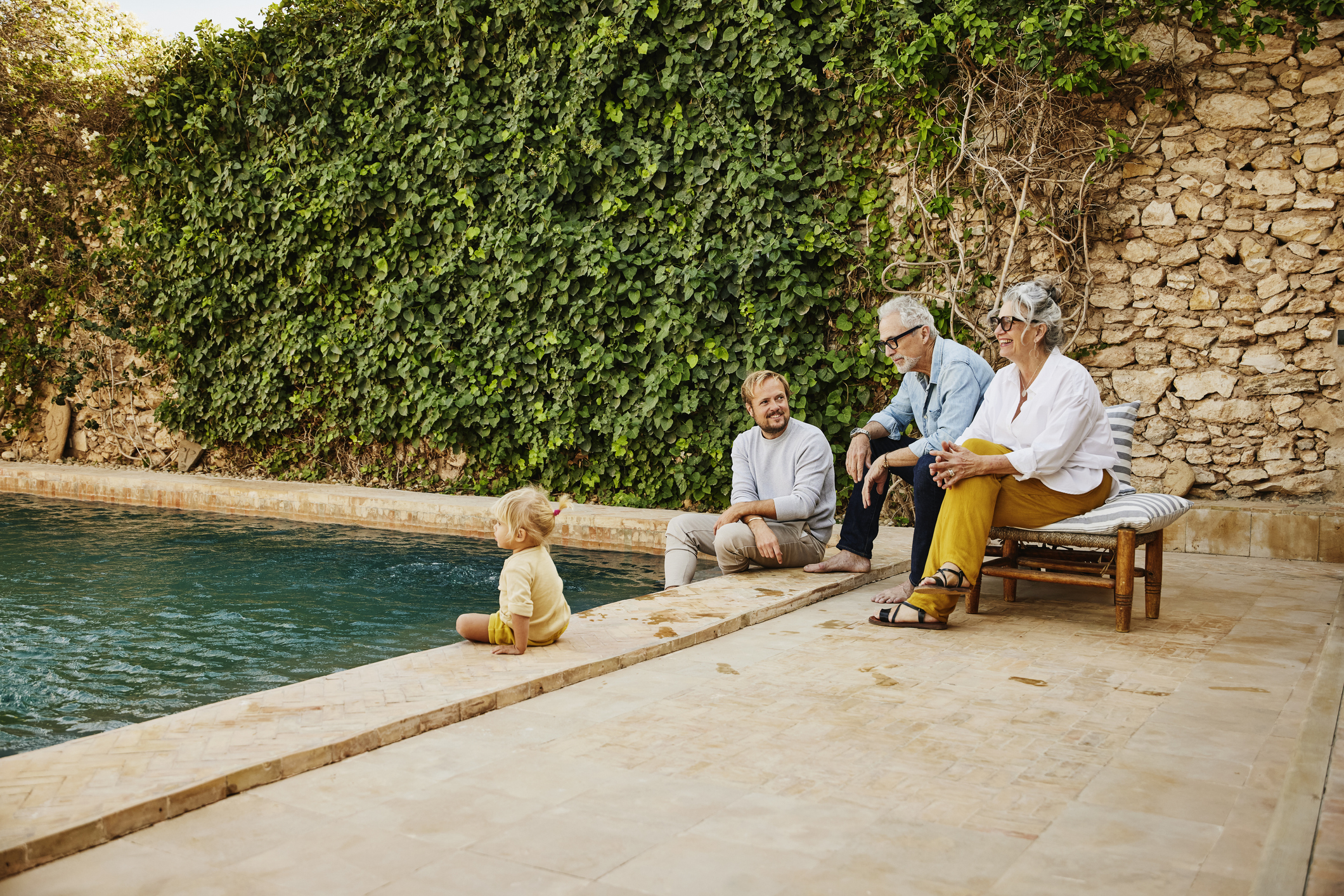 Wide shot smiling multigenerational family relaxing at tropical villa